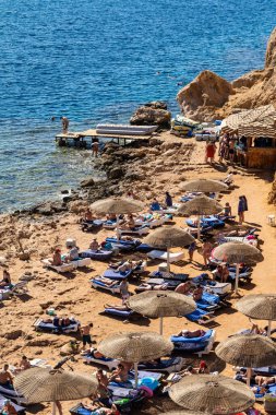 Sharm El Sheikh, Mısır - 1 Şubat 2020. Deniz kenarındaki plaj salonları, şemsiyeler, insanlar dinleniyor. Deniz kenarında yoğun bir yaz tatili. Güneşli bir gün, güneş banyosu, yüzme.