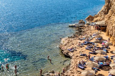Sharm El Sheikh, Mısır - 1 Şubat 2020: Deniz kenarında yoğun bir yaz tatili. Güneşli bir günde insanlar denizde ve sahilde, güneşleniyorlar, yüzüyorlar.