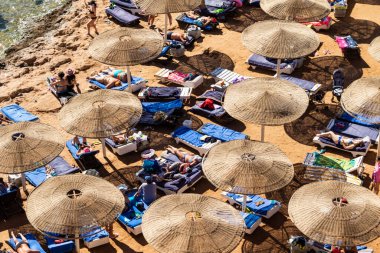 Sharm El Sheikh, Mısır - 1 Şubat 2020. Deniz kenarındaki plaj salonları, şemsiyeler, insanlar dinleniyor. Deniz kenarında yoğun bir yaz tatili. Güneşli bir gün, güneş banyosu, yüzme.