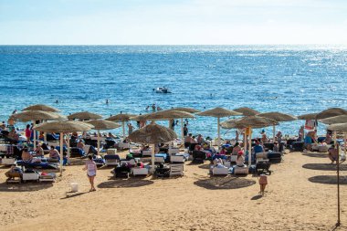 Sharm El Sheikh, Mısır - 1 Şubat 2020: Deniz kenarında yoğun bir yaz tatili. Güneşli bir günde insanlar denizde ve sahilde, güneşleniyorlar, yüzüyorlar.