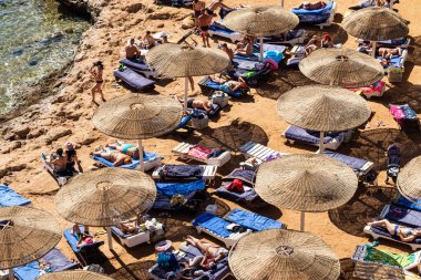 Sharm El Sheikh, Mısır - 1 Şubat 2020. Deniz kenarındaki plaj salonları, şemsiyeler, insanlar dinleniyor. Deniz kenarında yoğun bir yaz tatili. Güneşli bir gün, güneş banyosu, yüzme.