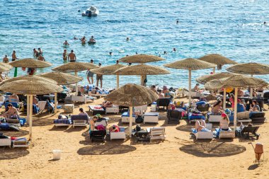 Sharm El Sheikh, Mısır - 1 Şubat 2020: Deniz kenarında yoğun bir yaz tatili. Güneşli bir günde insanlar denizde ve sahilde, güneşleniyorlar, yüzüyorlar.