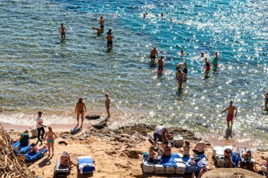 Sharm El Sheikh, Mısır - 1 Şubat 2020: Deniz kenarında yoğun bir yaz tatili. Güneşli bir günde insanlar denizde ve sahilde, güneşleniyorlar, yüzüyorlar.