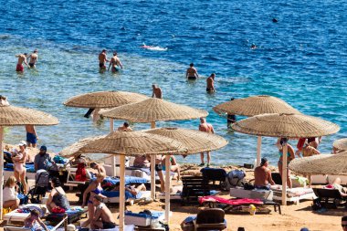 Sharm El Sheikh, Mısır - 1 Şubat 2020: Deniz kenarında yoğun bir yaz tatili. Güneşli bir günde insanlar denizde ve sahilde, güneşleniyorlar, yüzüyorlar.