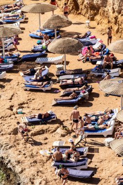 Sharm El Sheikh, Mısır - 1 Şubat 2020. Deniz kenarındaki plaj salonları, şemsiyeler, insanlar dinleniyor. Deniz kenarında yoğun bir yaz tatili. Güneşli bir gün, güneş banyosu, yüzme.