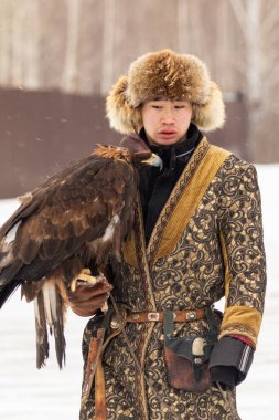 Petropavlovsk, Kazakistan - 20 Şubat 2020: Kazakistan, kuşlu bir avcının ulusal giysileri. Kışın sokaklarda kuş avlayan adamlar..