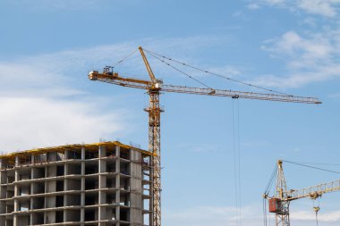 Ev inşaatında büyük bir vinç, mavi gökyüzü arka planı..