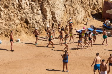 Sharm El Sheikh, Mısır - 10 Şubat 2020: kızlar ve kadınlar, erkekler deniz kıyısında dans ediyor. İnsanlar deniz sahilinde spor yapar. Deniz kenarında yoğun bir yaz tatili..