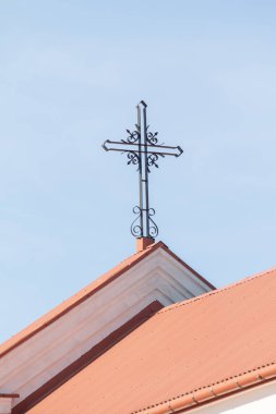 Mavi gökyüzüne karşı beyaz bir çatıda katolik haçı.