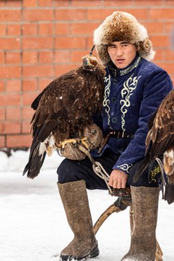 Petropavlovsk, Kazakistan - 20 Şubat 2020: Kazakistan, kuşlu bir avcının ulusal giysileri. Kışın sokaklarda kuş avlayan adamlar..
