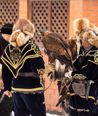 Petropavlovsk, Kazakistan - 20 Şubat 2020: Kazakistan, kuşlu bir avcının ulusal giysileri. Kışın sokaklarda kuş avlayan adamlar..
