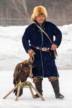 Petropavlovsk, Kazakistan - 20 Şubat 2020: Kazakistan, kuşlu bir avcının ulusal giysileri. Kışın sokaklarda kuş avlayan adamlar..