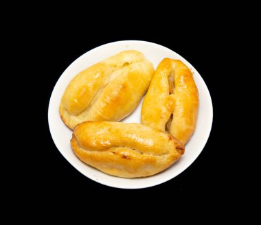 Pişmiş turtalar beyaz bir tabakta, siyah bir arka planda yatıyor..