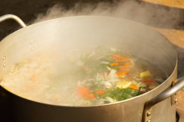 Büyük bir tencerenin üzerinde buharla çorba hazırlamak..