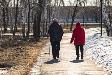 Kış parkında iki kadın kaldırımda yürüyor..