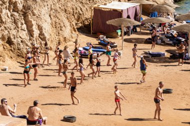 Sharm El Sheikh, Mısır - 10 Şubat 2020: kızlar ve kadınlar, erkekler deniz kıyısında dans ediyor. İnsanlar deniz sahilinde spor yapar. Deniz kenarında yoğun bir yaz tatili..
