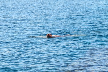 Maskeli bir adam suyun yüzeyinde yüzer. Deniz Burnu.