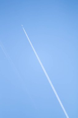 Mavi gökyüzündeki bir uçağın beyaz izi. Açık mavi gökyüzünde kanatlı bir yolcu uçağının izi.