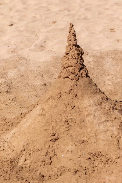 Playing with sand and building a sand castle on the seashore. Sand castle on the water. Sand castle on the beach.