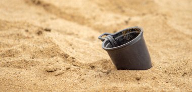 Kum üzerinde plastik bardak, kumsalda çöp..