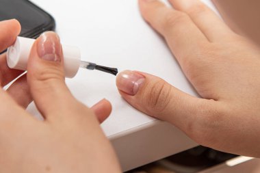 Kız, tırnaklarına oje sürerek yakın plan bir fırçayla oje sürüyor..