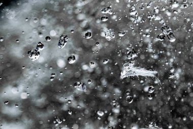 Karanlık arka planda su damlaları sınırlıdır. Kara zeminde donarak havaya düşen su damlaları..