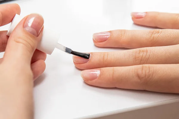 The girl paints her nails with nail Polish on her hands with a brush close-up.