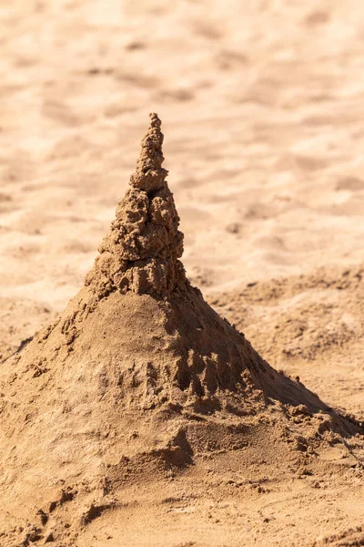 Playing with sand and building a sand castle on the seashore. Sand castle on the water. Sand castle on the beach.