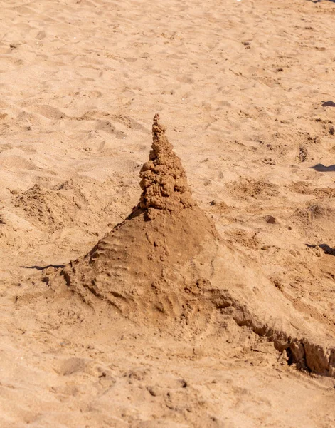 Playing with sand and building a sand castle on the seashore. Sand castle on the water. Sand castle on the beach.