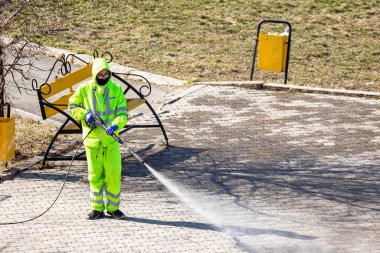 Petropavlovsk, Kazakistan - 11 Nisan 2020: Covid-19 virüsünün ortaya çıkmasıyla bağlantılı olarak şehir merkezindeki sokak ve sokakların temizlenmesi, temizlenmesi ve dezenfekte edilmesi. Koruyucu elbiseli takım.