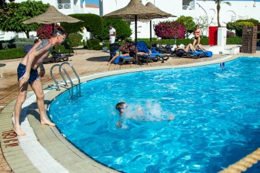Sharm El Sheikh, Mısır - 28 Ocak 2020: Yetişkinler ve çocuklar havuzda yüzer, güneşli bir günde slaytlara binerler. Başka bir deyişle, seyahat, tatil kavramı..