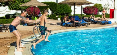 Sharm El Sheikh, Mısır - 28 Ocak 2020: Yetişkinler ve çocuklar havuzda yüzer, güneşli bir günde slaytlara binerler. Başka bir deyişle, seyahat, tatil kavramı..