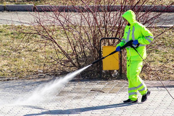 Петропавловск, Казахстан - 11 апреля 2020 года: санитария, очистка и дезинфекция улиц и переулков в центре города в связи с появлением вируса Ковид-19. Команда в защитных костюмах
.