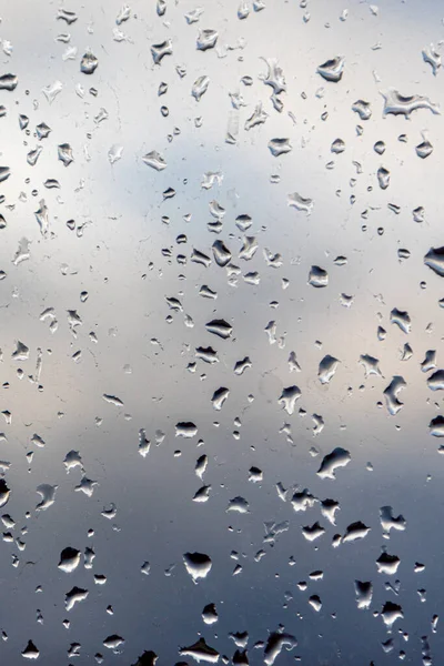 雨の雲と青い空の背景にガラスの上に雨滴 — ストック写真