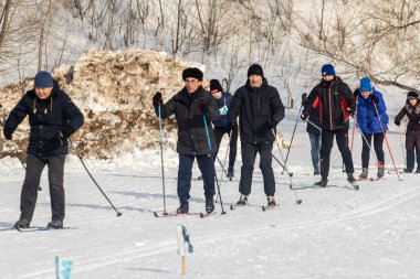 Petropavlovsk, Kazakistan - 29 Şubat 2020: Erkekler ve kadınlar, çocuklar kışın ormanda kayak yapıyor. Güneşli kış manzarası, kayak. Petropavlovsk, Kazakistan.