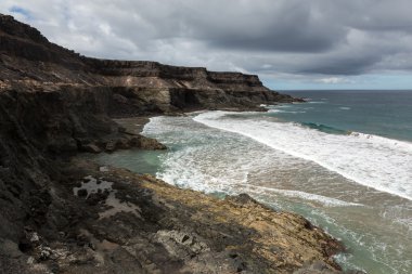 Puertito beach de los Molinos Fuerteventura üzerinde bir kayaya üzerine sıçramasına el salla. Kanarya Adaları, İspanya