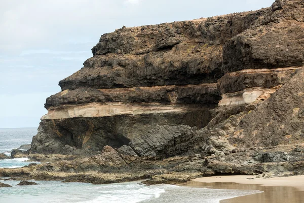 Vinka stänk över en klippa på stranden av Puertito de los Molinos på Fuerteventura. Kanarieöarna, Spanien — Stockfoto
