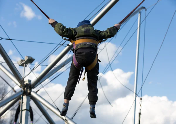 A gyerekek jó szórakozást a gumiszalaggal biztosított bungee trambulinon ugráláshoz. — Stock Fotó
