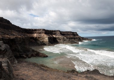 Puertito beach de los Molinos Fuerteventura üzerinde bir kayaya üzerine sıçramasına el salla. Kanarya Adaları, İspanya