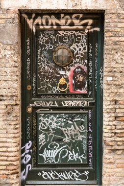  Grafiti Trastevere bölgesinde ile eski ahşap kapı kapalı. Roma, İtalya.