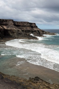 Puertito beach de los Molinos Fuerteventura üzerinde bir kayaya üzerine sıçramasına el salla. Kanarya Adaları, İspanya