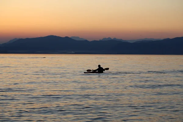 Remador solitário no lago durante o pôr do sol — Fotografia de Stock