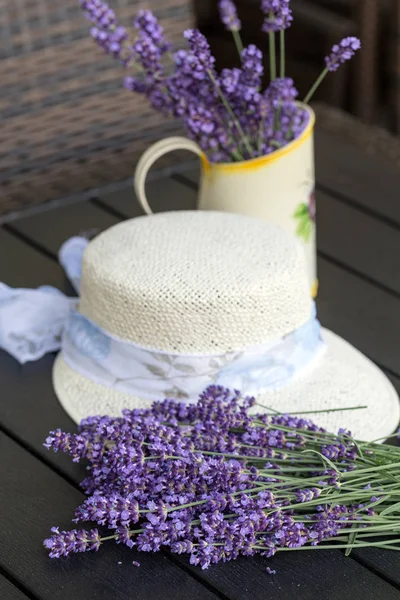 Fiori di lavanda e cappello bianco sul tavolo nero — Foto Stock
