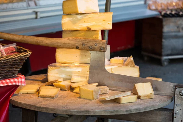 Käse zum verkauf und ein alter schneider oder hacker zum aufschneiden von käse auf einem markt in salzburg — Stockfoto