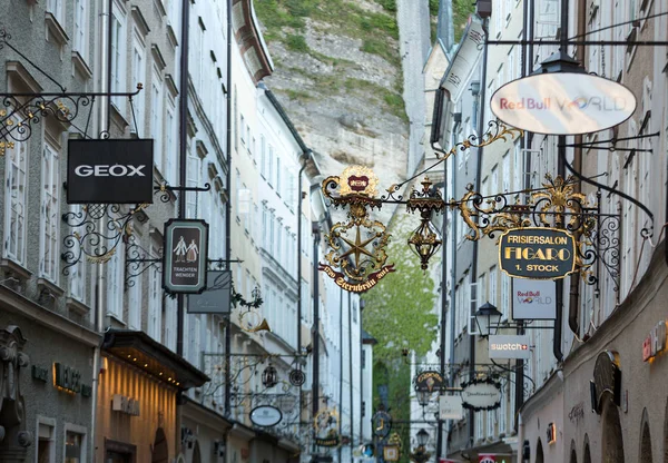 Calle comercial en Salzburgo Getreidegasse con múltiples carteles publicitarios. Getreidegasse, es una de las calles más antiguas de Salzburgo —  Fotos de Stock