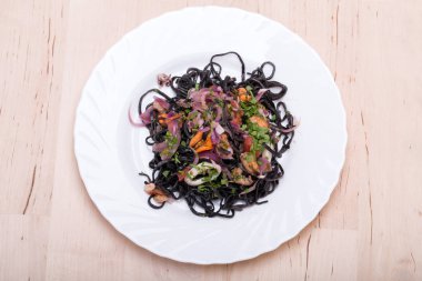 Deniz ürünleri ve sebze ile siyah spagetti.