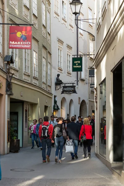 Niet-geïdentificeerde mensen lopen op beroemde historische winkelstraat straat Getreidegasse in Salzburg — Stockfoto
