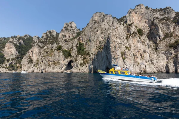 Gemilerde teknedeki turist ve Uçurumun kıyısında ve Capri Adası ile görüntüleyin. İtalya