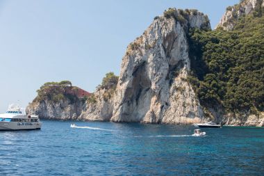 Gemilerde teknedeki turist ve Uçurumun kıyısında ve Capri Adası ile görüntüleyin. İtalya