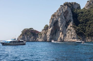 Gemilerde teknedeki turist ve Uçurumun kıyısında ve Capri Adası ile görüntüleyin. İtalya
